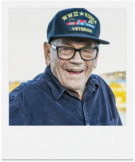 Smiling veteran in a WWII and Korea veteran cap