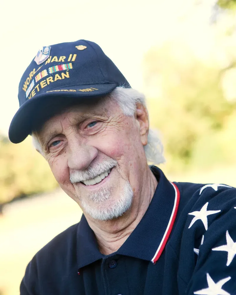 Smiling veteran wearing a WWII veteran cap